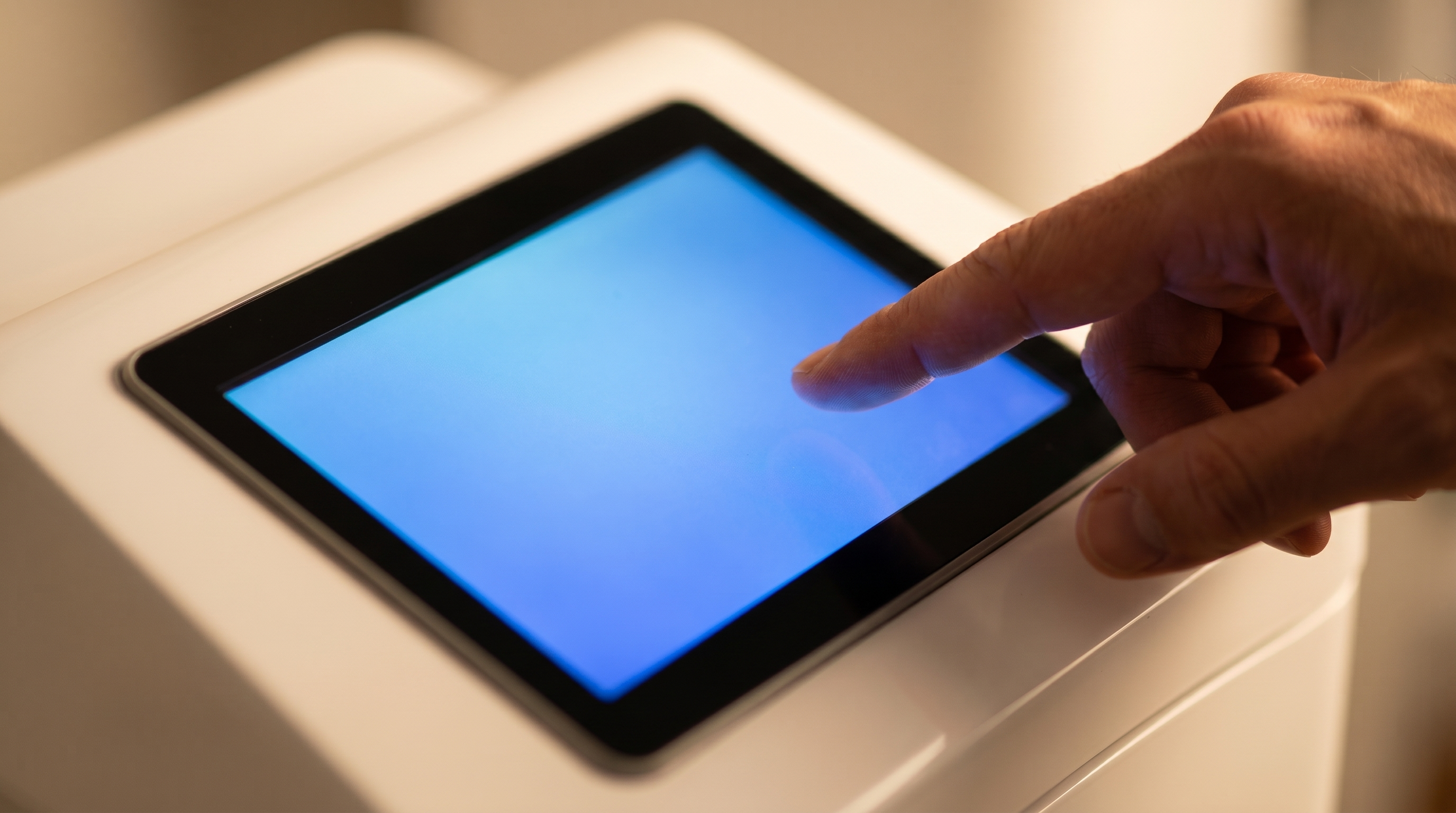 A hand reaching for the touch panel on top of the console, the screen lit oxygen-blue.